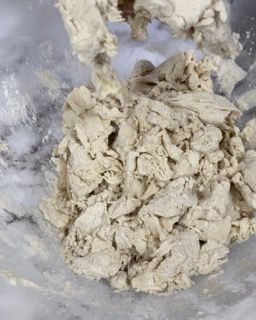 Un primo piano di una ciotola di pasta con un cucchiaio di legno dentro