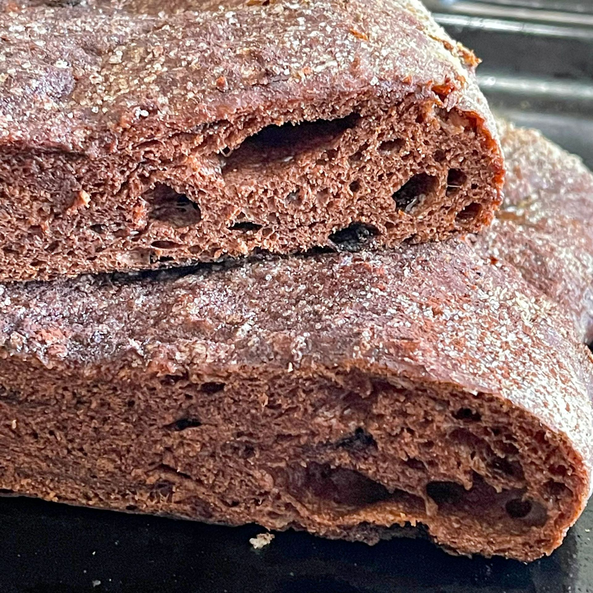 Due fette di pane al cioccolato sono impilate una sopra l'altra su una superficie nera.