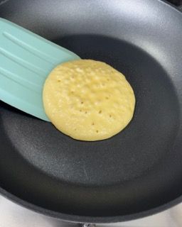 Un pancake viene cucinato in una padella con una spatola