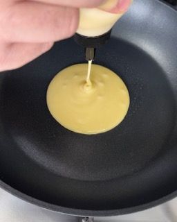Una persona sta versando la pastella per pancake in una padella.