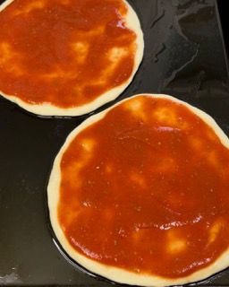 Due pizze ricoperte di salsa di pomodoro su un tavolo