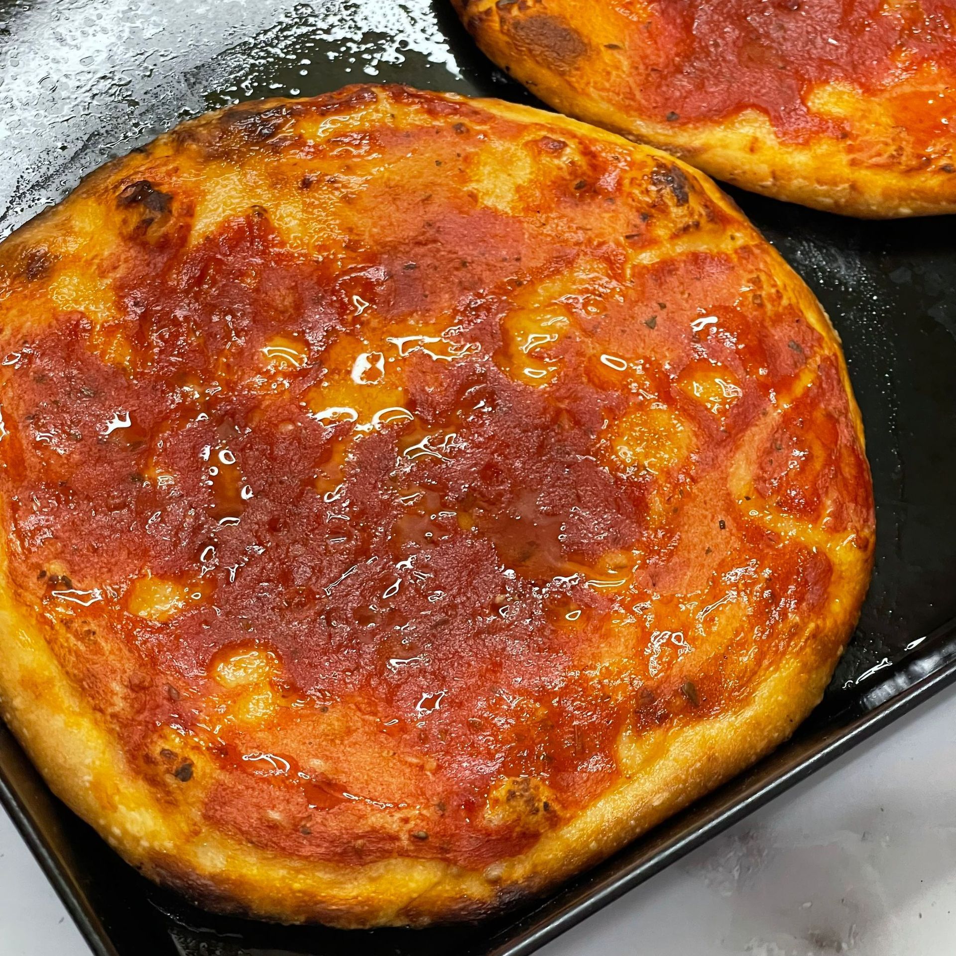 Due pizze sono appoggiate su un vassoio nero su un tavolo.