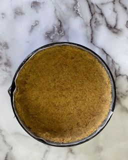 Una ciotola piena di polvere marrone è appoggiata su una superficie di marmo.
