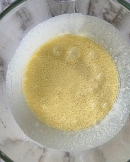 Primo piano di una ciotola di liquido giallo su un tavolo.