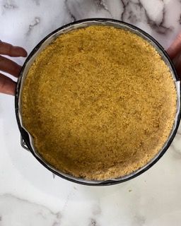 Una persona tiene in mano una pasta per torta in una teglia.