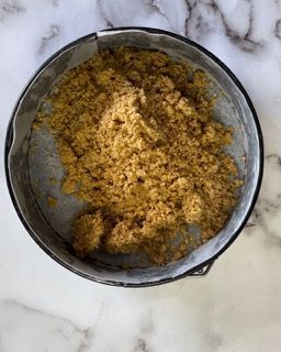 Una padella piena di briciole su una superficie di marmo.