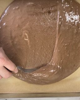 Una persona sta versando l'impasto della torta al cioccolato in una teglia