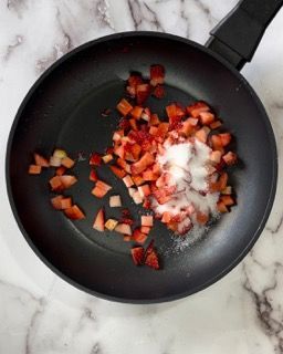 Fragole e zucchero vengono cotti in una padella.
