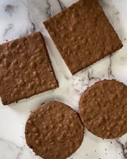 Tre cracker al cioccolato sono appoggiati su una superficie di marmo.