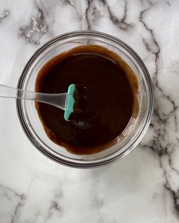 Una ciotola di salsa al cioccolato con un cucchiaio dentro su un tavolo.