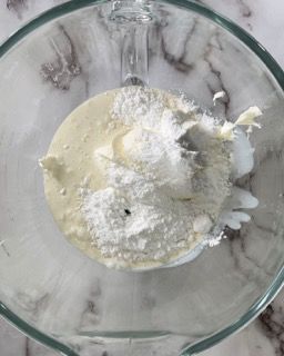 Una ciotola di vetro piena di un liquido bianco e zucchero a velo.