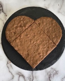 Un biscotto a forma di cuore su un piatto nero