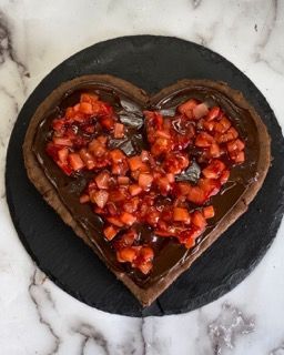 Una torta al cioccolato a forma di cuore con fragole sopra
