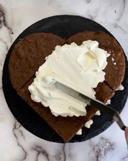 Una torta a forma di cuore con panna montata spalmata sopra
