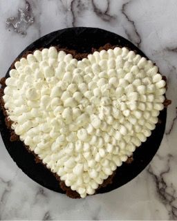 Una torta a forma di cuore con glassa bianca e marshmallow