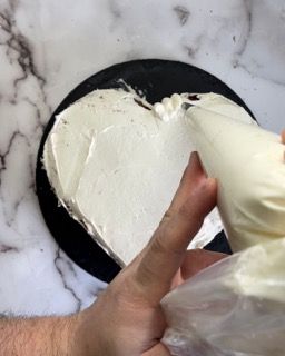 Una persona sta glassando una torta a forma di cuore