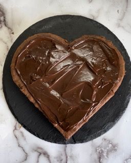 Un biscotto a forma di cuore con crema al cioccolato sopra