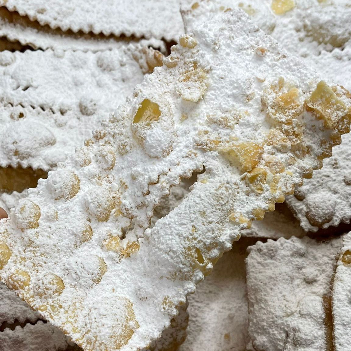 Abbondante spolverata di zucchero a velo sulle chiacchiere ricetta originale finite.
