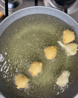 Una padella piena di olio e cibo fritto su un fornello.