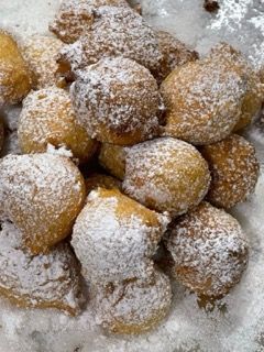 Una pila di ciambelle ricoperte di zucchero a velo su un tavolo.