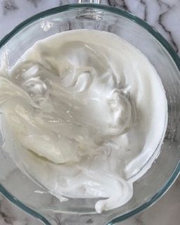 Una ciotola di vetro piena di liquido bianco è appoggiata su un tavolo.