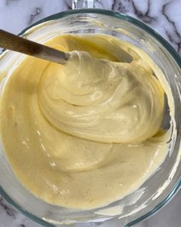 Una ciotola di salsa gialla con un cucchiaio dentro.
