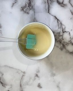 Una ciotola piena di liquido con una spatola dentro su una superficie di marmo.