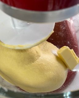 Un pezzetto di burro viene aggiunto all'impasto nella planetaria.