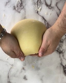 Una persona tiene in mano una palla di pasta.