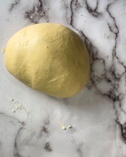 Una palla di pasta è appoggiata su una superficie di marmo.
