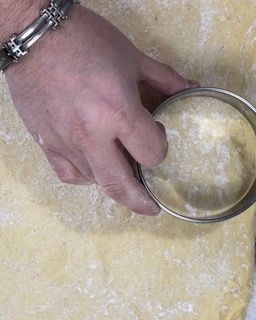 Una persona sta usando uno stampino per biscotti per tagliare un pezzo di pasta.