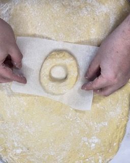 Una persona sta preparando una ciambella su un pezzo di carta oleata.