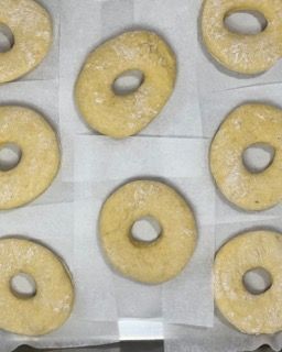 Un mucchio di ciambelle sono appoggiate su un pezzo di carta oleata