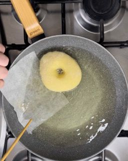 Una persona sta cucinando una ciambella in una padella