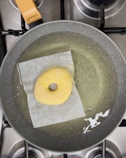 Una ciambella viene cotta in una padella sul fornello.