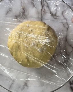 Una palla di pasta è avvolta in pellicola trasparente su una superficie di marmo.