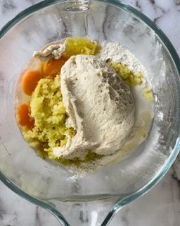Una ciotola di vetro piena di purè di patate, burro e farina.