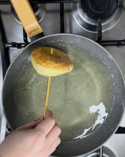 Una persona sta mettendo una ciambella su un bastoncino in una padella