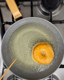 Una ciambella viene cotta in una padella sul fornello