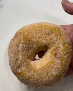 Una persona tiene in mano una ciambella di zucchero.