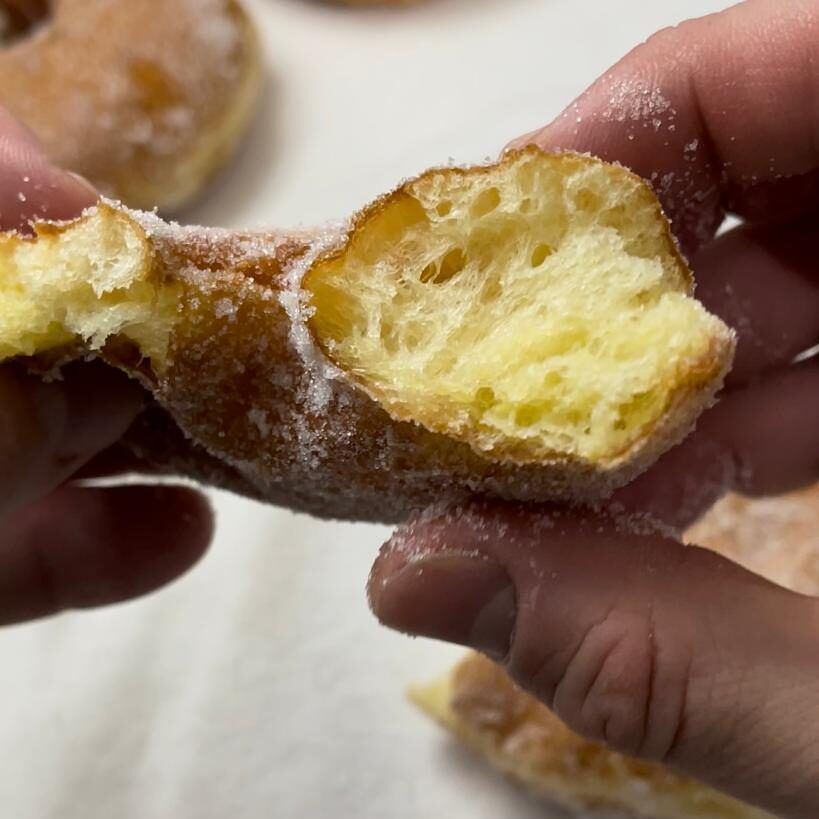 Una persona tiene in mano una ciambella con un morso