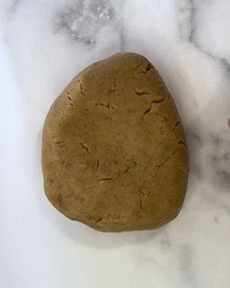 Un pezzo di pasta marrone è appoggiato su una superficie bianca.