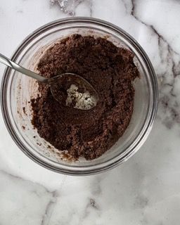Una ciotola di cioccolato in polvere con un cucchiaio dentro.