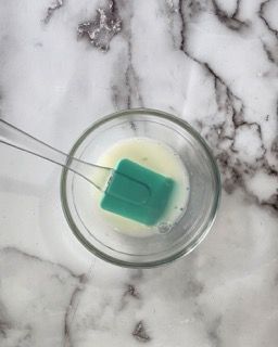 Una ciotola di liquido con una spatola verde dentro.