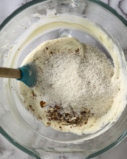 Una ciotola di vetro riempita con un composto di zucchero a velo e noci.