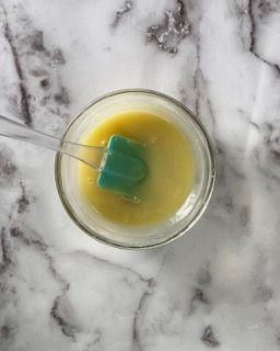 Una ciotola di liquido giallo con una spatola verde dentro.
