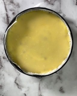 Una ciotola piena di liquido giallo è appoggiata su una superficie di marmo.