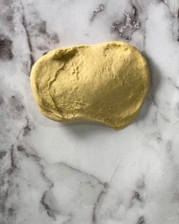 Un pezzo di pasta è appoggiato su una superficie di marmo.