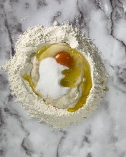 Primo piano di una ciotola di farina con un uovo dentro.
