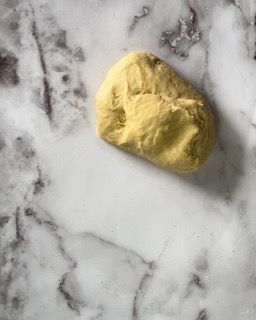 Una palla di pasta è appoggiata su una superficie di marmo.